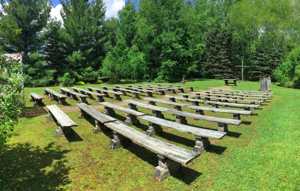 a row of wooden benches sitting on top of a lush green field